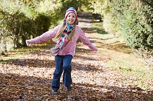 Young girl outdoors at park running on path smiling (selective focus)