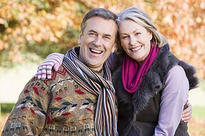 Couple outdoors in park embracing and smiling (selective focus)