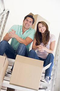 Couple sitting on staircase with boxes in new home smiling
