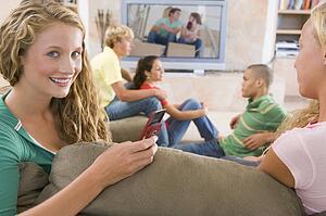Teenagers Hanging Out In Front Of Television Using Mobile Phones 