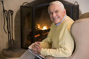 Man in living room with newspaper smiling