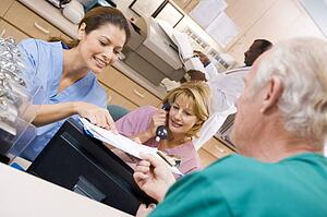 Nurses Discussing A Clipboard At The Reception Area In A Hospital