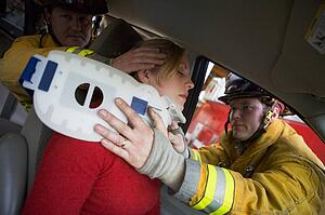 Two firemen helping woman with neck brace