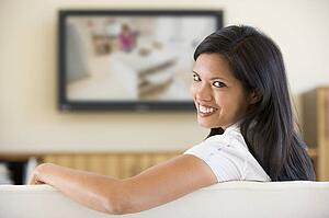 Woman in living room watching television smiling