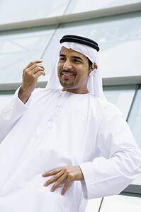 Businessman outdoors by building wearing headset and smiling