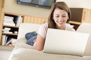 Woman in living room using laptop smiling