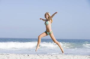 Woman in a two piece bathing suit running on a beach
