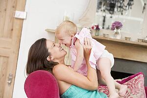 Pregnant mother in living room holding daughter and laughing