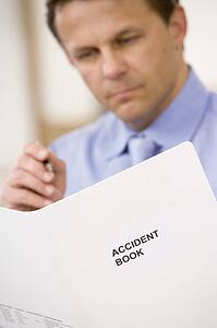 Businessman indoors looking at Accident Book