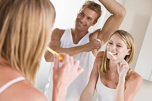 Couple in bathroom brushing teeth and applying deodorant