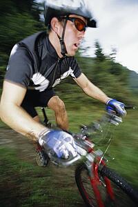 Man outdoors on trails riding bicycle (out of focus)