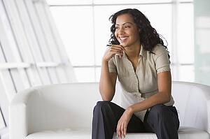 Businesswoman sitting indoors smiling (high key/selective focus)