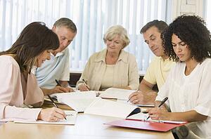 Five adult students studying at table (depth of field)