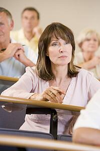 Woman sitting in adult classroom with students in background (selective focus)