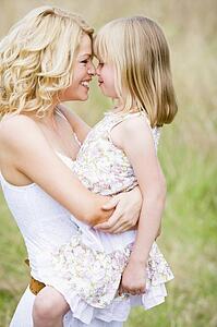 Mother holding daughter outdoors smiling