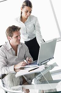 Two businesspeople in boardroom with laptop