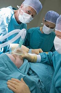 Three Surgeons Operating On A Patient