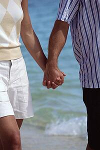 Couple holding hands outdoors at the beach (selective focus)