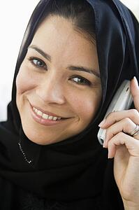 Woman indoors on cellular phone smiling (high key)