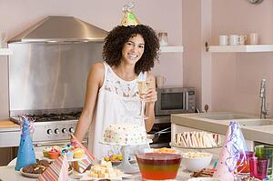 Woman at party holding drink standing by food table smiling