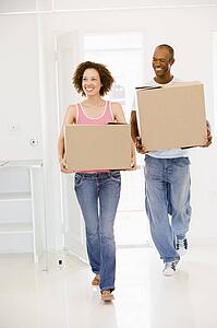 Couple with boxes moving into new home smiling