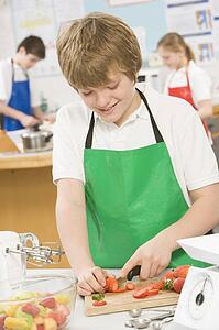 Male student slicing berries in cooking class