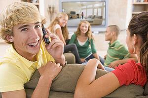 Teenagers Hanging Out In Front Of Television Using Mobile Phones 