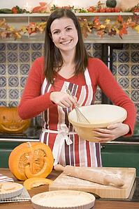 Woman in kitchen making Halloween treats and smiling