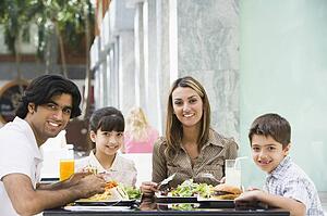 Family at restaurant eating and smiling (selective focus)