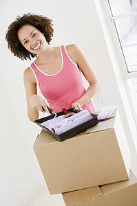Woman with roller and paint in new home smiling