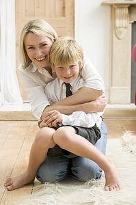 Woman in front hallway hugging young boy and smiling