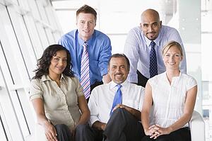 Five businesspeople indoors smiling (high key/selective focus)
