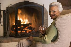 Woman in living room with drink smiling