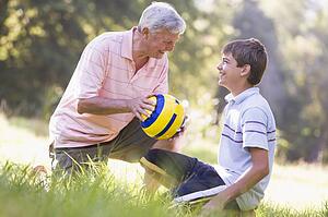 Grandfather and grandson at a park with a ball smiling