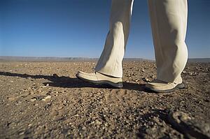 Man's legs walking through desert landscape