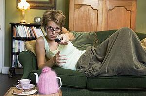 Young woman lying on sofa at home watching television
