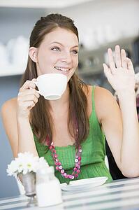 Young woman sitting at a table drinking tea