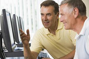 Two men at a computer terminal talking (depth of field/high key)