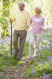 Couple walking outdoors with walking stick smiling