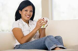 Woman in living room with coffee smiling