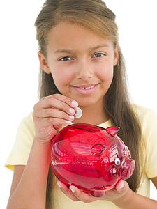 Young girl putting coin into piggy bank smiling