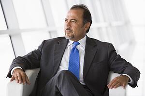 Businessman sitting indoors looking out window (high key/selective focus)