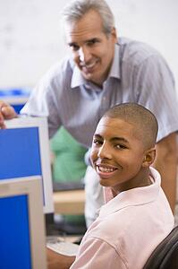 Teacher with male student in computer class