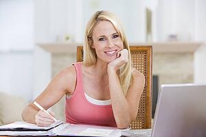 Woman in dining room with laptop smiling