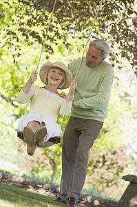 Couple outdoors with tree swing smiling