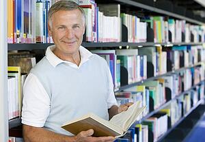Man in library holding book (depth of field)