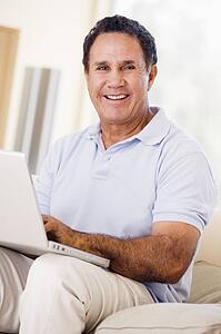 Man in living room with laptop smiling