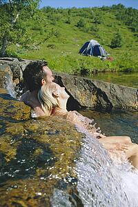 Couple outdoors by campsite relaxing in stream