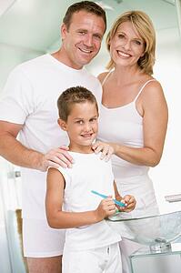 Couple in bathroom with young boy brushing teeth