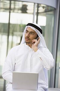 Man outdoors with laptop and cellular phone by building (selective focus)